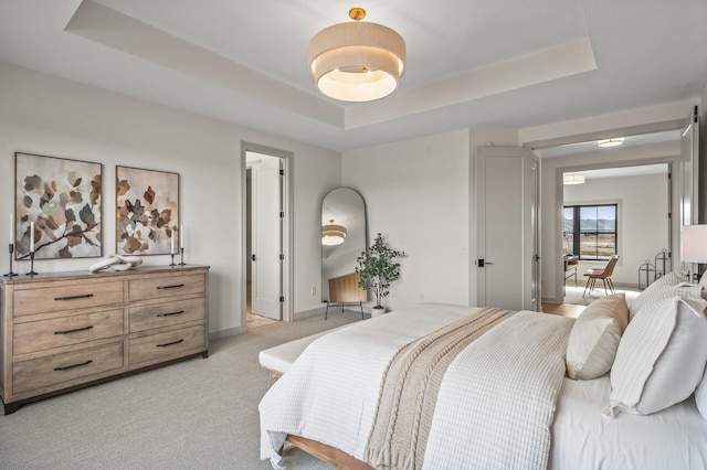 bedroom with baseboards, a raised ceiling, and light colored carpet