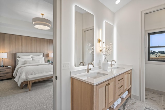 ensuite bathroom with baseboards, marble finish floor, a sink, and connected bathroom