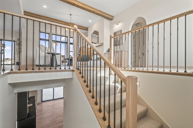 staircase featuring plenty of natural light, wood finished floors, beamed ceiling, and recessed lighting