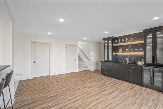 bar with visible vents, wine cooler, stairway, and light wood-style flooring