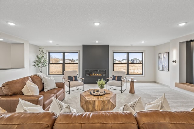 living area with baseboards, a glass covered fireplace, a textured ceiling, and light colored carpet