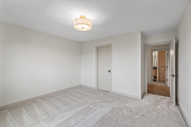 unfurnished bedroom featuring a closet, light colored carpet, and baseboards