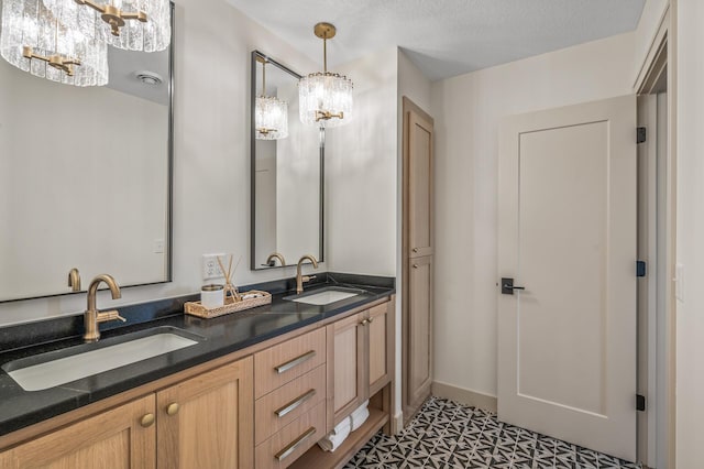 bathroom featuring double vanity, an inviting chandelier, a textured ceiling, and a sink