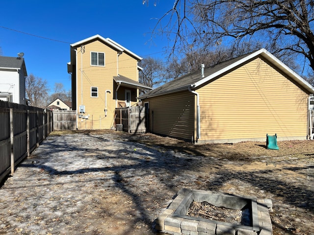 back of house featuring an outdoor fire pit and fence