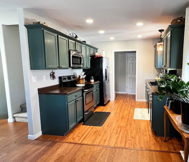 kitchen with appliances with stainless steel finishes, dark countertops, recessed lighting, and light wood-style floors