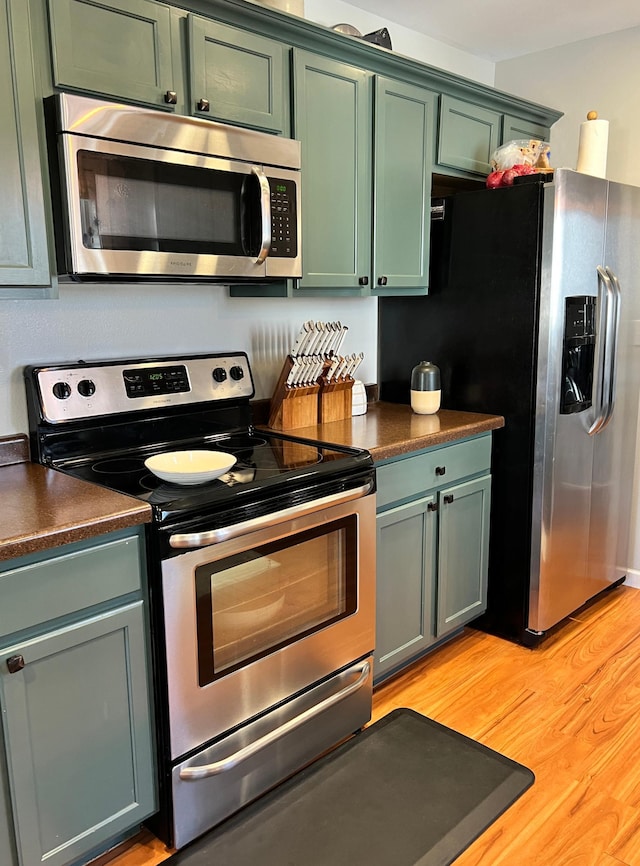 kitchen with stainless steel appliances, dark countertops, and green cabinetry