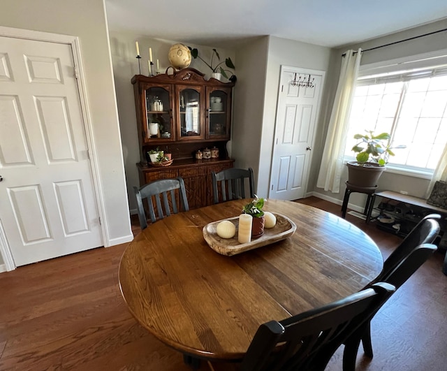 dining space featuring dark wood-type flooring and baseboards