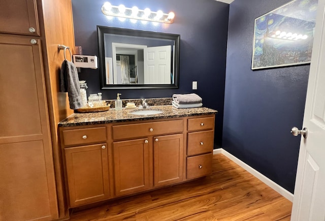 bathroom featuring baseboards, wood finished floors, and vanity