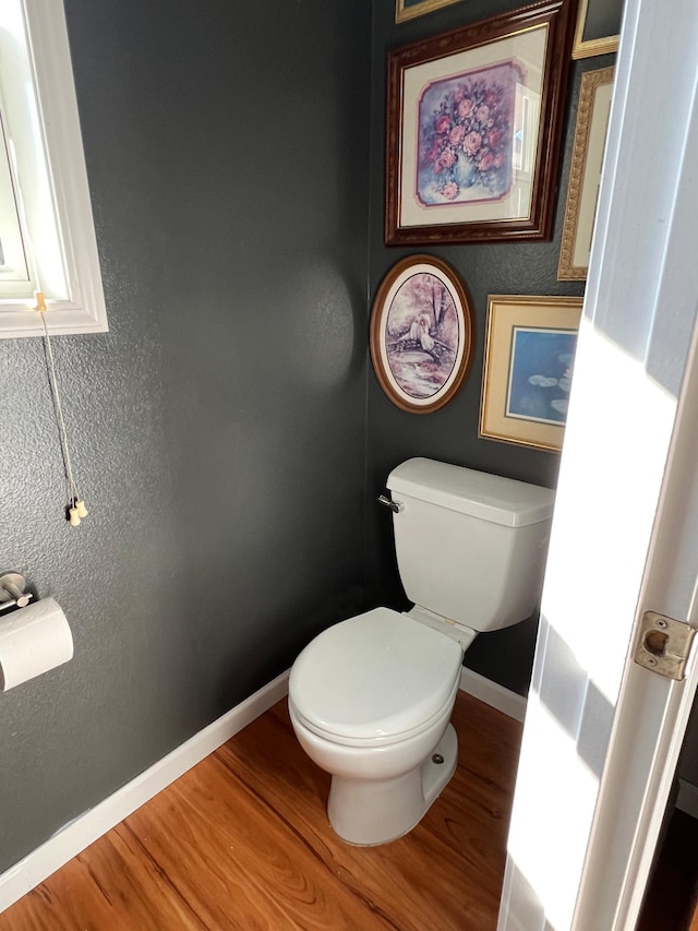 bathroom with baseboards, toilet, and wood finished floors