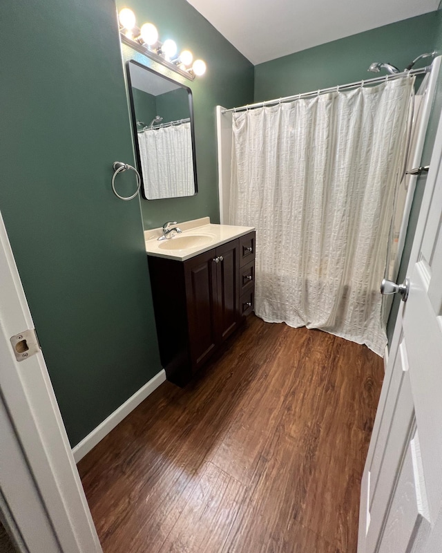 bathroom featuring a shower with curtain, wood finished floors, vanity, and baseboards