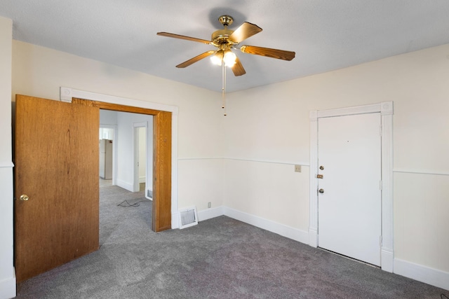 unfurnished room with carpet, visible vents, ceiling fan, and baseboards