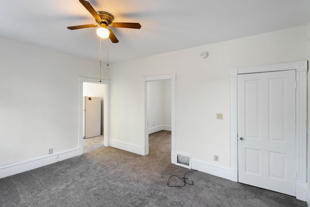 unfurnished bedroom featuring carpet floors, visible vents, a ceiling fan, baseboards, and freestanding refrigerator