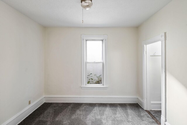 spare room with carpet, a textured ceiling, and baseboards