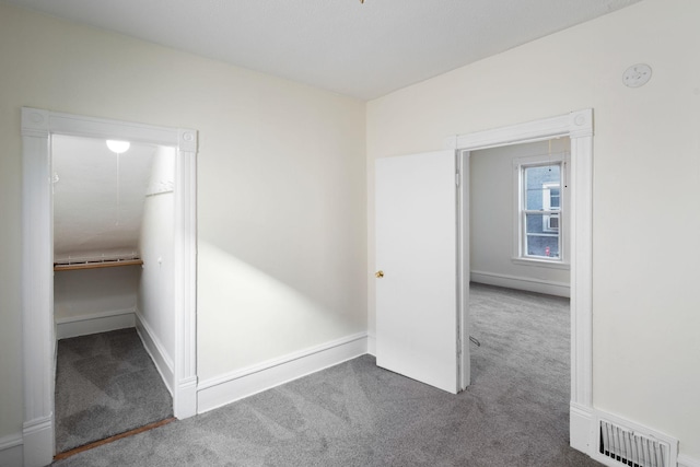 unfurnished bedroom featuring baseboards, a spacious closet, visible vents, and carpet flooring