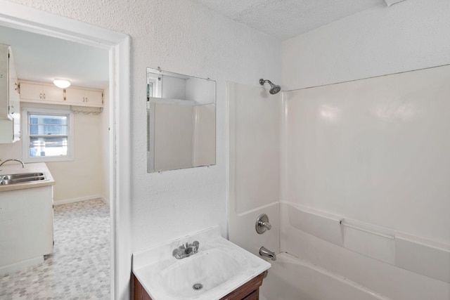 bathroom featuring  shower combination, a textured wall, vanity, and a textured ceiling