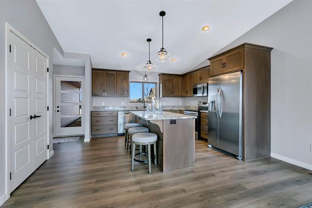 kitchen with a kitchen bar, appliances with stainless steel finishes, vaulted ceiling, and dark wood-type flooring