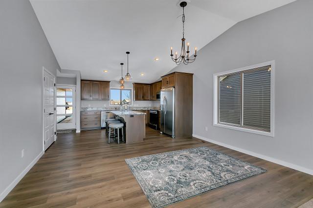 kitchen with a breakfast bar area, dark wood-type flooring, light countertops, appliances with stainless steel finishes, and a center island with sink