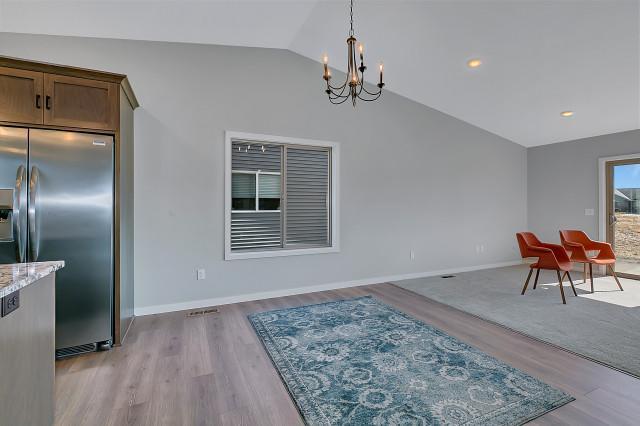 dining space featuring lofted ceiling, light wood-style flooring, baseboards, and a notable chandelier