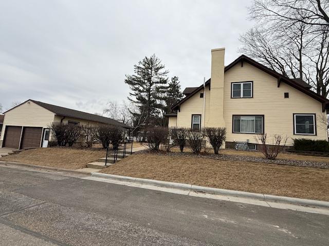 view of property exterior featuring a garage, an outbuilding, and a chimney