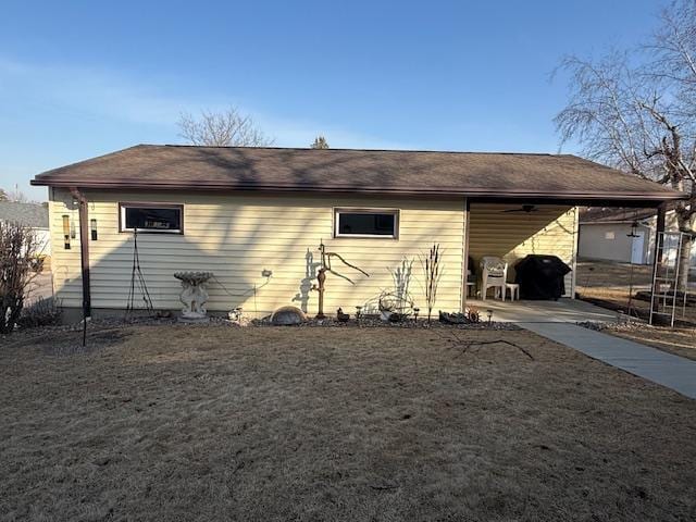 rear view of house with driveway, an attached carport, and a lawn