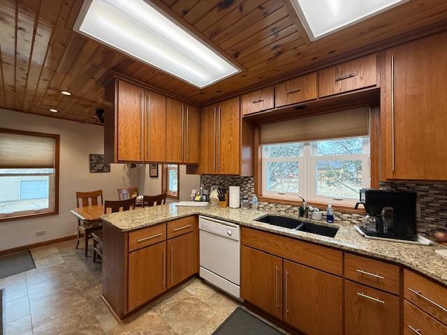 kitchen featuring a peninsula, white dishwasher, a sink, and brown cabinets