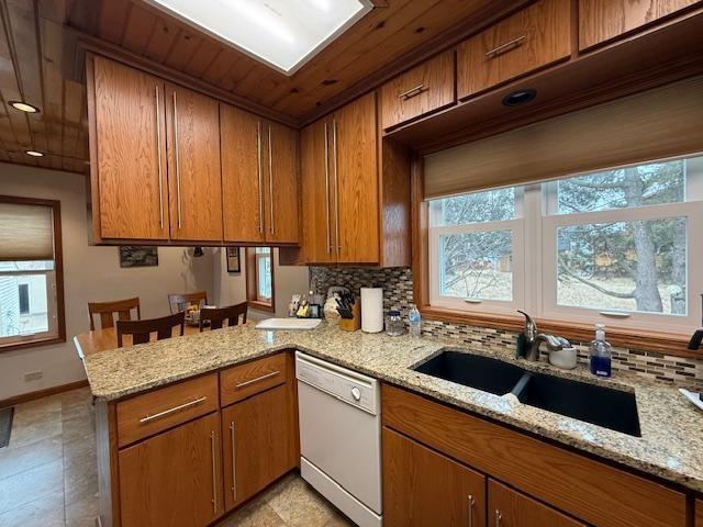 kitchen featuring a healthy amount of sunlight, dishwasher, a peninsula, and a sink