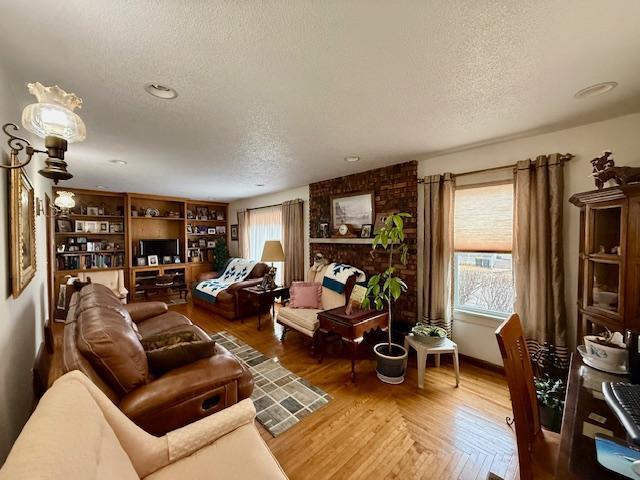 living area featuring a fireplace, a textured ceiling, and wood finished floors