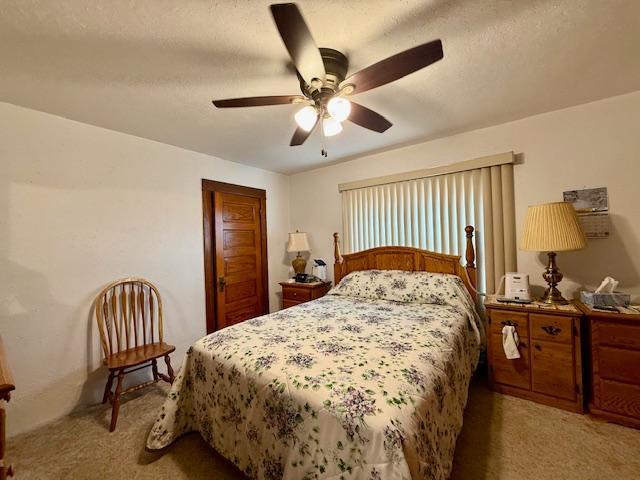 bedroom with a closet, a ceiling fan, a textured ceiling, and light colored carpet