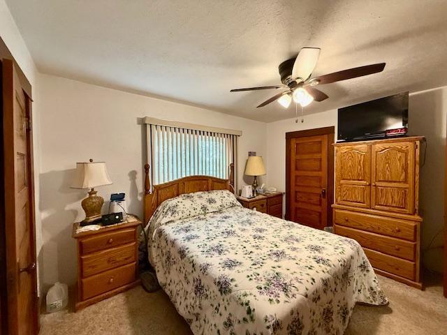 bedroom with light carpet, ceiling fan, and a textured ceiling