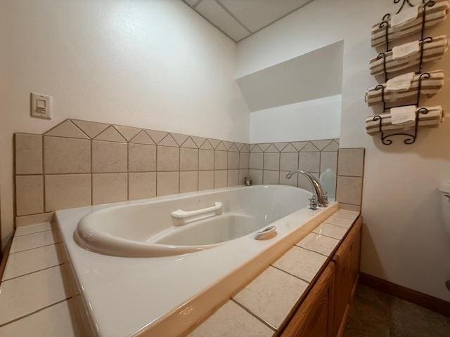 full bath with toilet, a garden tub, and baseboards