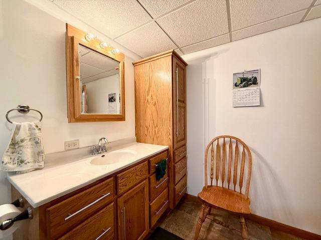 bathroom featuring a paneled ceiling and vanity