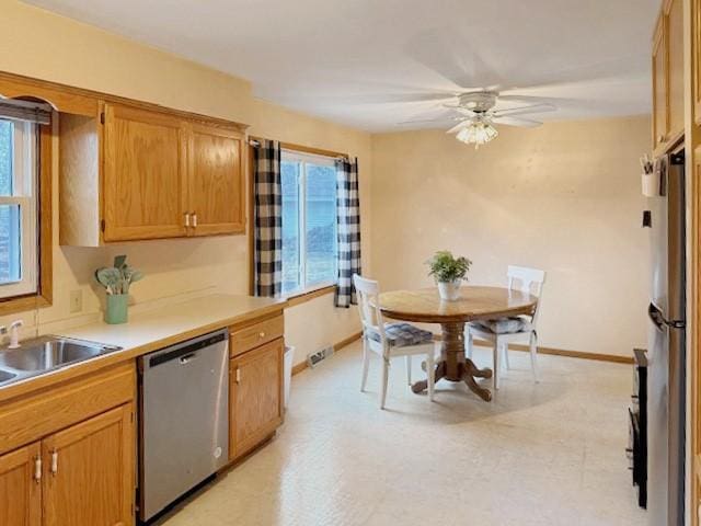 kitchen featuring ceiling fan, light floors, baseboards, and stainless steel appliances