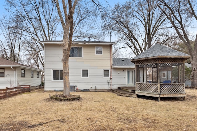 rear view of house with a lawn, a deck, fence, a gazebo, and a shingled roof