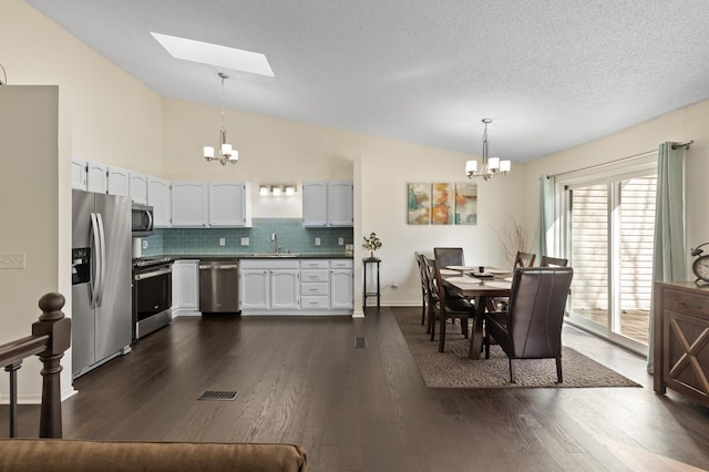 kitchen featuring a sink, appliances with stainless steel finishes, vaulted ceiling, and a notable chandelier