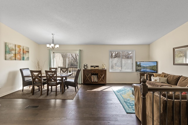 dining room with a chandelier, a textured ceiling, lofted ceiling, wood finished floors, and baseboards