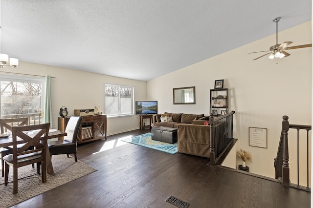 living area with baseboards, visible vents, lofted ceiling, dark wood-style floors, and a textured ceiling