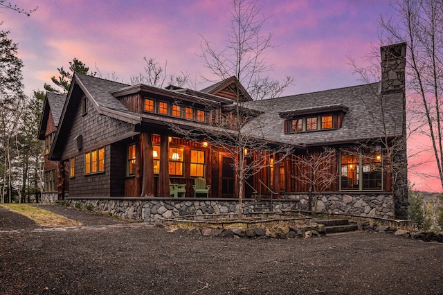 view of front of house with a chimney, roof with shingles, and covered porch