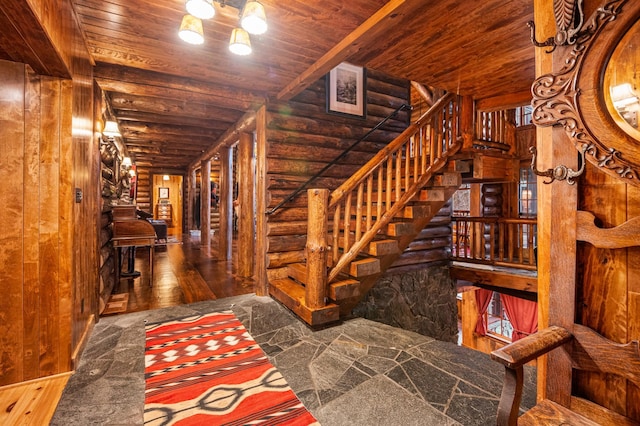 stairway with log walls, wooden ceiling, and wood finished floors