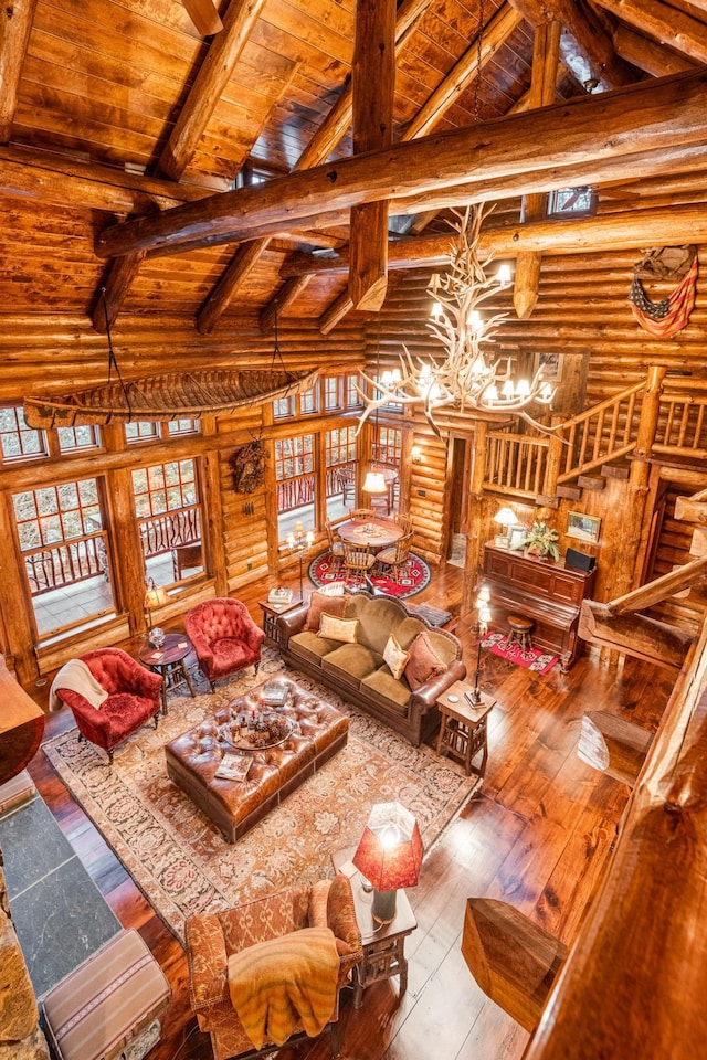 living area featuring log walls, wooden ceiling, beamed ceiling, a chandelier, and wood-type flooring