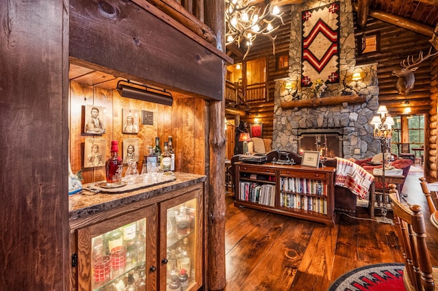 indoor dry bar featuring rustic walls, wood-type flooring, high vaulted ceiling, beamed ceiling, and a fireplace