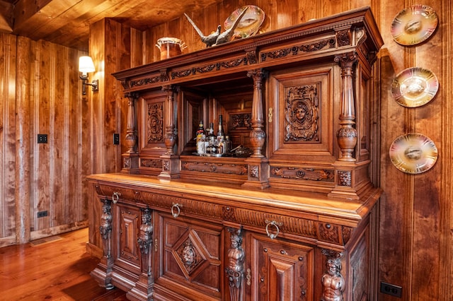 bar area with wood walls, light wood-type flooring, and wood ceiling