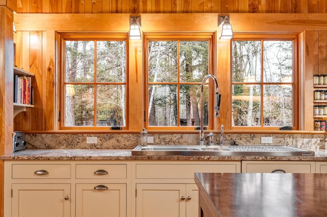 kitchen featuring a sink, light countertops, white cabinets, and wood walls