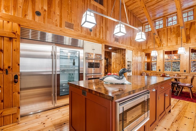 kitchen featuring built in appliances, light wood-style flooring, wooden walls, wooden counters, and wood ceiling