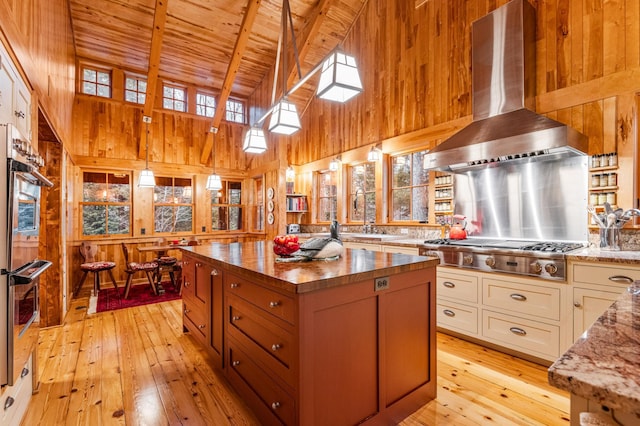 kitchen featuring wall chimney range hood, wood ceiling, wood walls, butcher block counters, and light wood-style floors