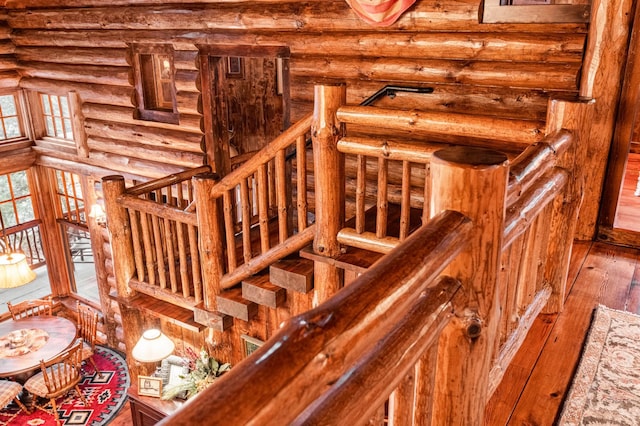 stairs featuring rustic walls and hardwood / wood-style flooring