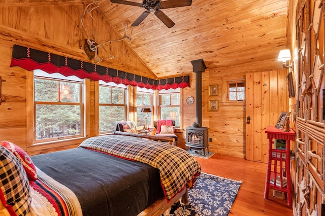 bedroom featuring wooden ceiling, a wood stove, lofted ceiling, wooden walls, and multiple windows