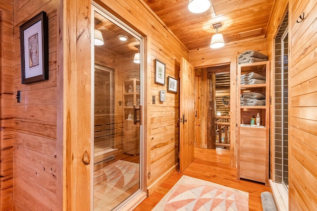 relaxing sauna / steam room featuring wooden walls, wood ceiling, and wood finished floors