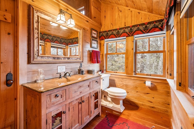 bathroom featuring wooden walls, wood finished floors, toilet, wooden ceiling, and lofted ceiling