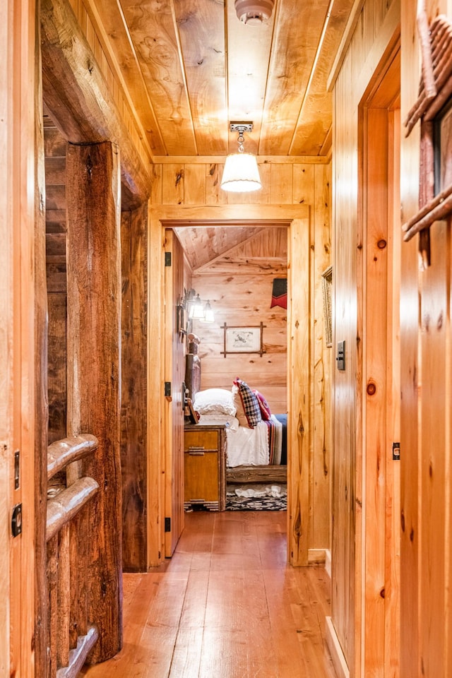 corridor featuring wooden walls, hardwood / wood-style flooring, and wood ceiling