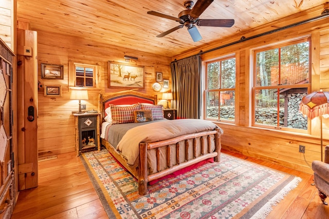 bedroom with wooden walls, wooden ceiling, and hardwood / wood-style flooring